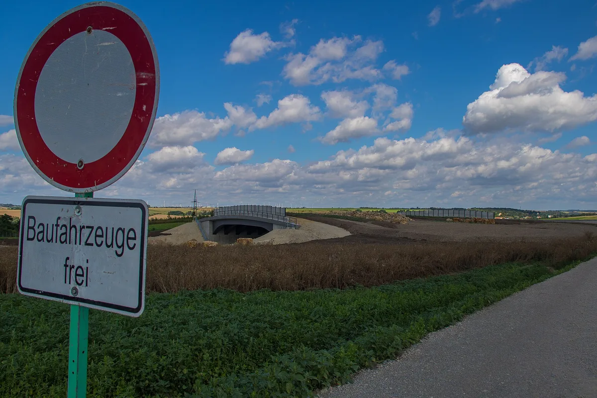 Bewachsene Grünbrücke führt über eine mehrspurige Autobahn zwischen Waldstücken