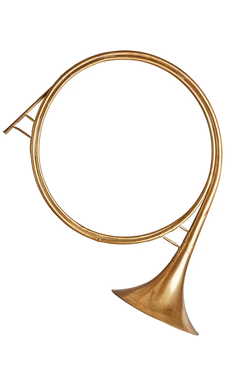 Gewundenes messingfarbenes Parforcehorn ohne Ventile vor weißem Grund
